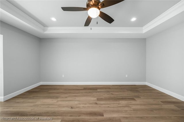 unfurnished room with hardwood / wood-style floors, ceiling fan, ornamental molding, and a tray ceiling