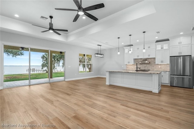 kitchen featuring ceiling fan, light stone countertops, decorative light fixtures, white cabinetry, and stainless steel refrigerator