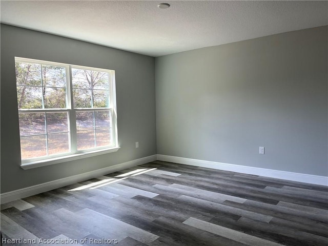 unfurnished room with a textured ceiling and dark wood-type flooring