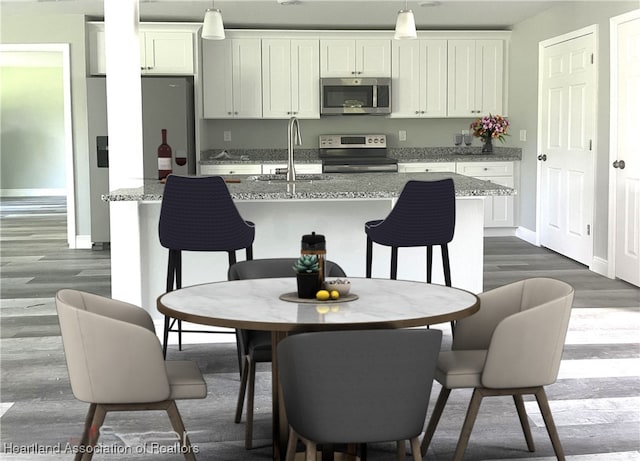 kitchen featuring white cabinets, stainless steel appliances, hanging light fixtures, and sink