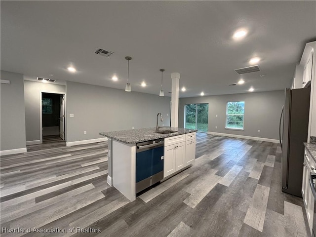 kitchen featuring white cabinetry, sink, hanging light fixtures, stainless steel appliances, and a center island with sink