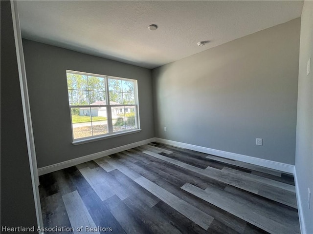 empty room with a textured ceiling and dark wood-type flooring