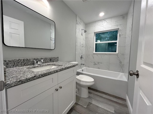 full bathroom featuring toilet, vanity, wood-type flooring, and tiled shower / bath