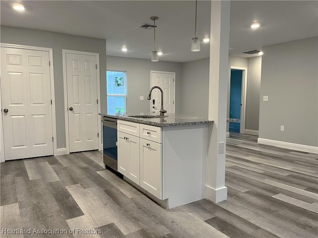 kitchen featuring light stone countertops, stainless steel dishwasher, sink, pendant lighting, and white cabinets