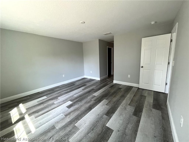 empty room featuring a textured ceiling and dark hardwood / wood-style floors