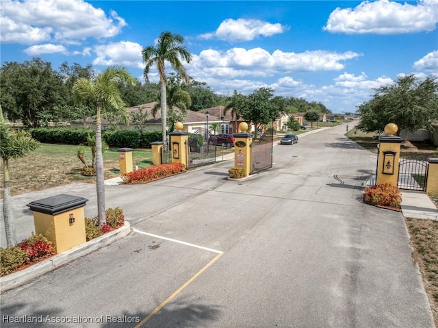 view of street featuring a gate, a gated entry, and curbs