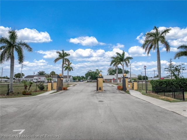 view of road featuring sidewalks, a gated entry, and a gate