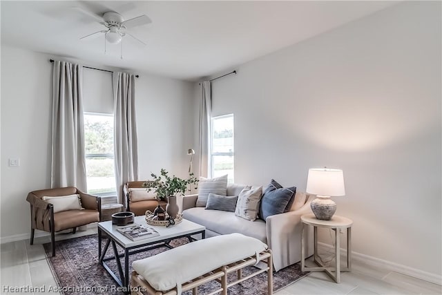 living area with baseboards and ceiling fan