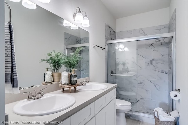 bathroom featuring toilet, a sink, a marble finish shower, and double vanity