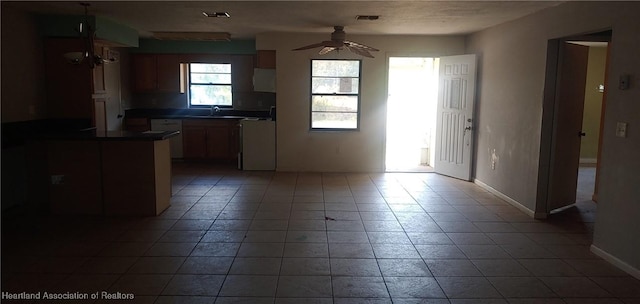 kitchen featuring dark countertops, visible vents, ceiling fan, a sink, and baseboards