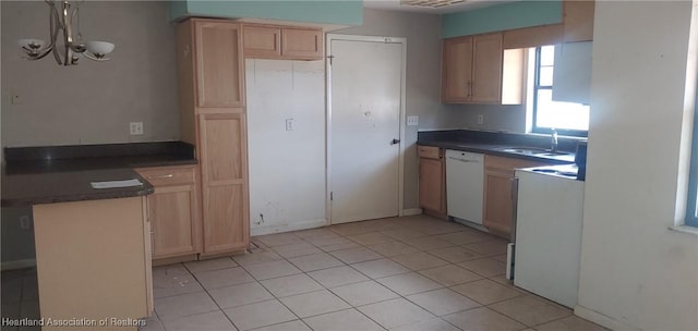 kitchen with dark countertops, white dishwasher, a sink, and light brown cabinetry