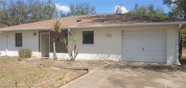 ranch-style home with a garage, concrete driveway, roof with shingles, and stucco siding