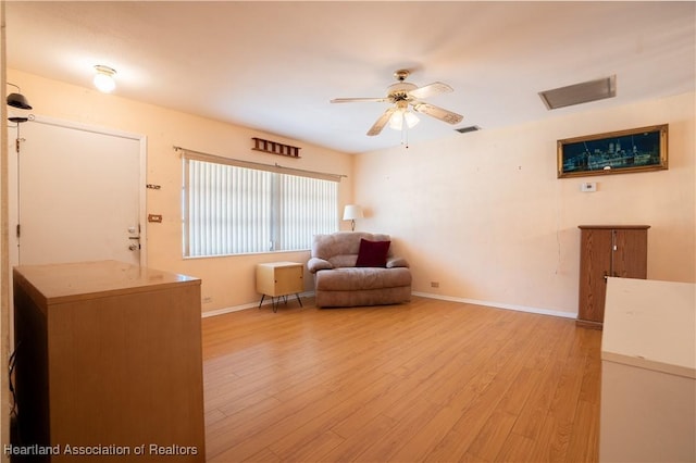 living area featuring light wood-type flooring, baseboards, visible vents, and ceiling fan