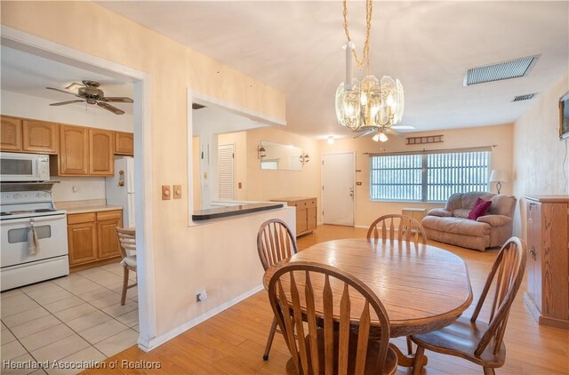 dining area with visible vents, baseboards, light wood-style floors, and ceiling fan with notable chandelier