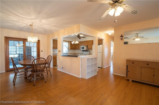 dining area with ceiling fan with notable chandelier, light wood-style floors, and baseboards