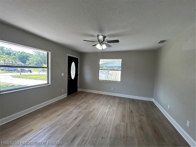 unfurnished room featuring hardwood / wood-style floors, ceiling fan, and a textured ceiling