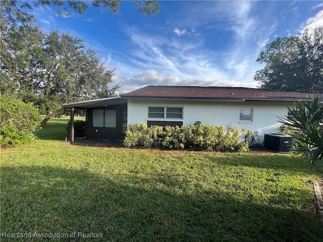 rear view of house featuring central AC unit and a lawn