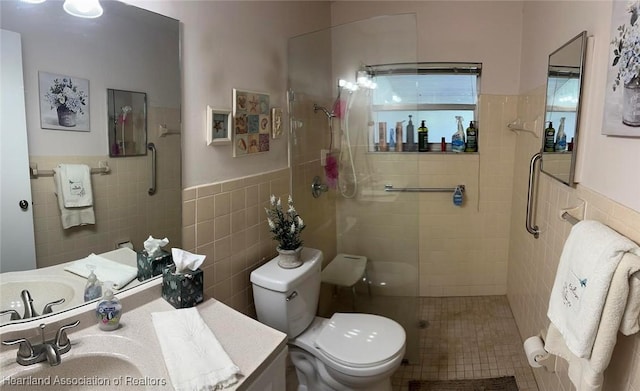 bathroom featuring a tile shower, vanity, toilet, and tile walls