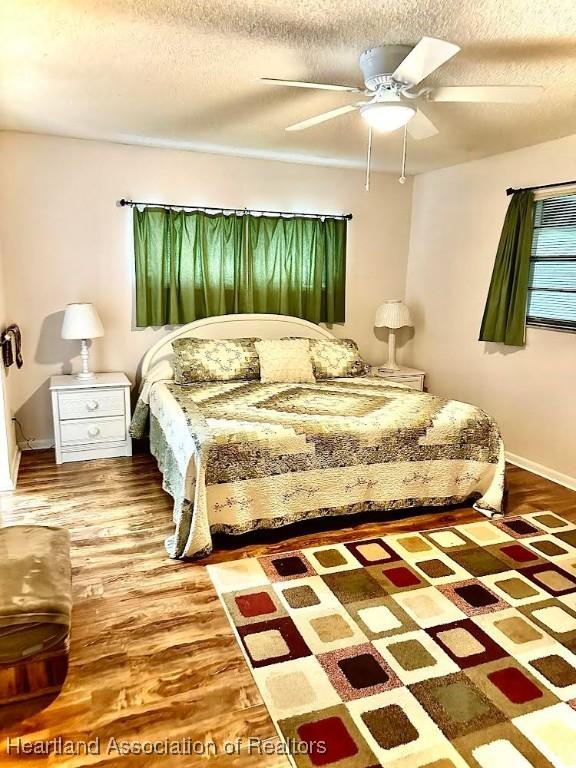 bedroom featuring wood-type flooring, a textured ceiling, and ceiling fan