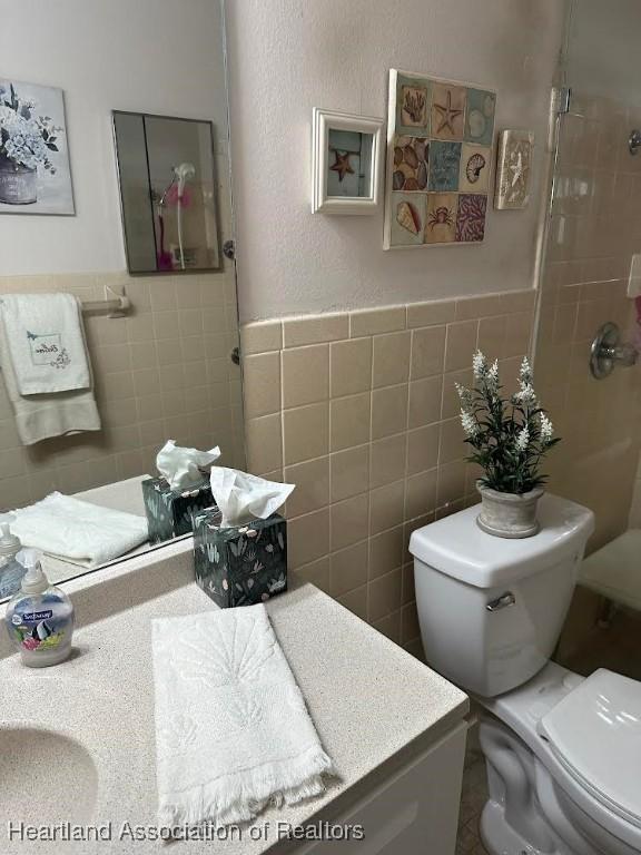 bathroom featuring vanity, toilet, and tile walls