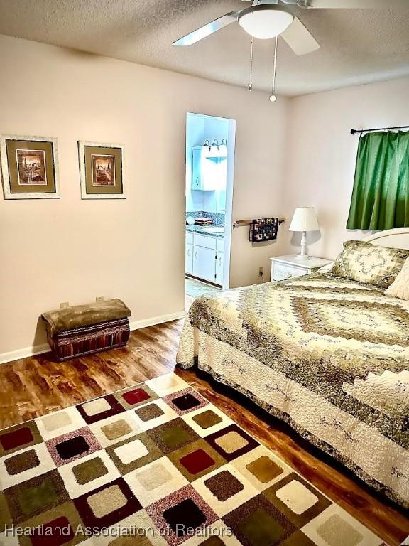 bedroom featuring hardwood / wood-style flooring, ceiling fan, a textured ceiling, and ensuite bath