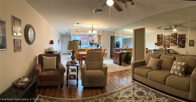 living room featuring hardwood / wood-style flooring, ceiling fan with notable chandelier, and a textured ceiling