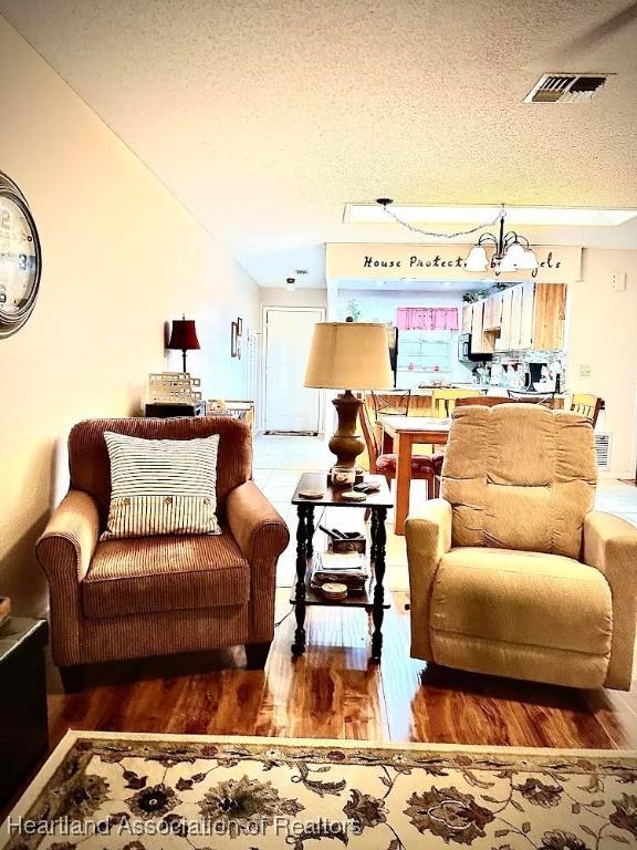 living room featuring hardwood / wood-style floors, a textured ceiling, and an inviting chandelier