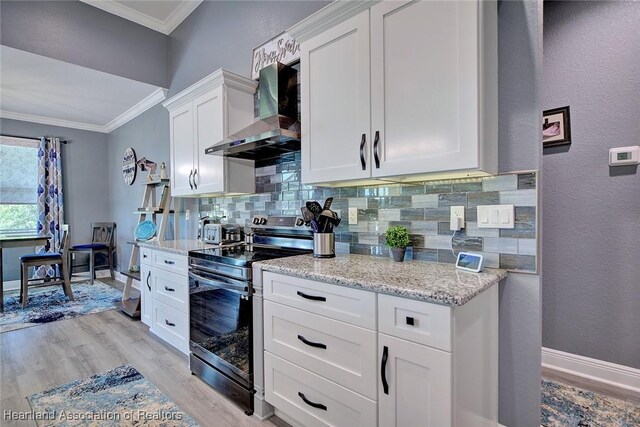 kitchen featuring electric stove, light wood-style floors, wall chimney exhaust hood, backsplash, and ornamental molding