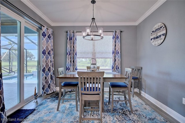dining room featuring ornamental molding, an inviting chandelier, wood finished floors, and baseboards