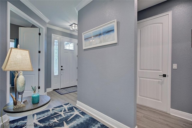 foyer with wood finished floors, crown molding, and baseboards
