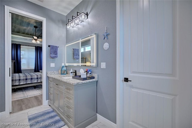 bathroom featuring ceiling fan, ensuite bath, vanity, and baseboards