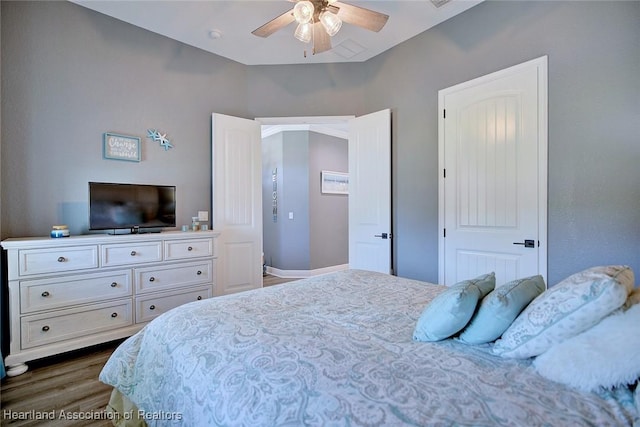 bedroom with dark wood-style floors, a ceiling fan, and baseboards