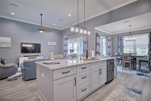 kitchen featuring visible vents, a sink, white cabinetry, and light wood-type flooring