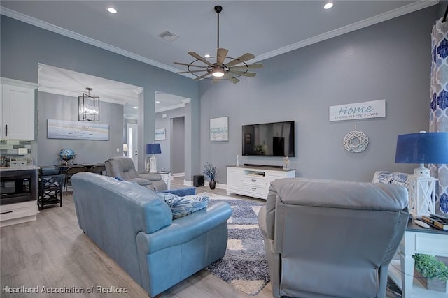 living area with recessed lighting, light wood-type flooring, crown molding, visible vents, and ceiling fan with notable chandelier