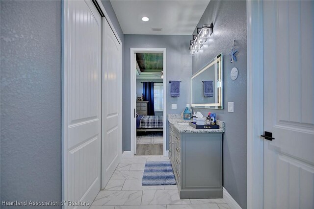 bathroom with baseboards, a textured wall, vanity, and marble finish floor