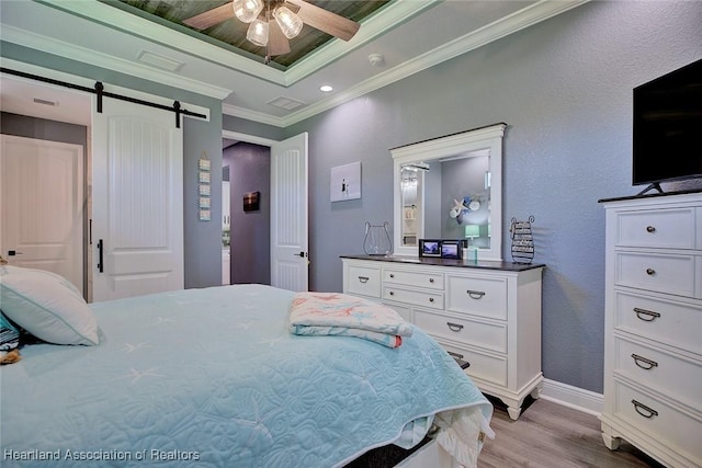 bedroom with light wood finished floors, a barn door, a ceiling fan, baseboards, and ornamental molding