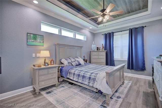 bedroom featuring ornamental molding, light wood-type flooring, and a tray ceiling