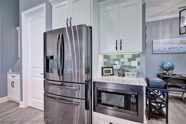 kitchen with light wood-style flooring, light stone counters, appliances with stainless steel finishes, and tasteful backsplash