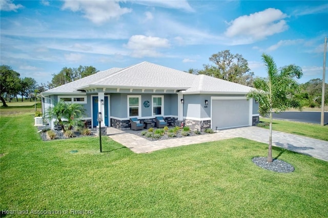 view of front facade featuring stucco siding, decorative driveway, a garage, outdoor lounge area, and a front yard