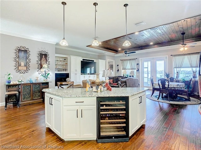 kitchen featuring white cabinetry, hanging light fixtures, beverage cooler, a kitchen island, and wood ceiling