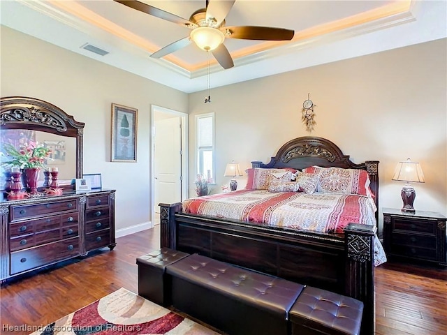 bedroom with a raised ceiling, ceiling fan, dark hardwood / wood-style floors, and ornamental molding