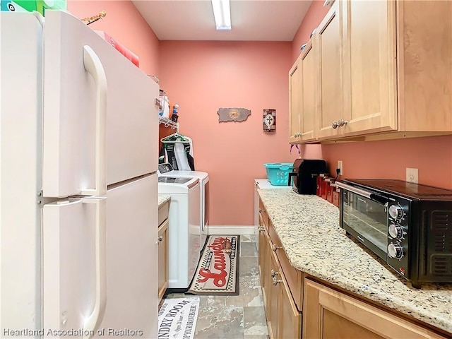 kitchen featuring light stone countertops, light brown cabinetry, white fridge, and washer and dryer