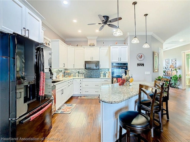 kitchen featuring hanging light fixtures, white cabinetry, crown molding, and black appliances