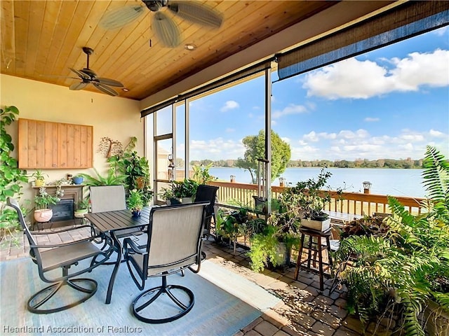 sunroom with ceiling fan, a water view, and wooden ceiling