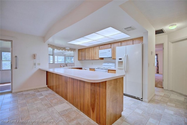 kitchen with visible vents, light countertops, a peninsula, plenty of natural light, and white appliances