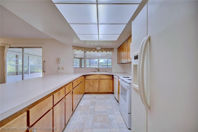 kitchen featuring white appliances, light countertops, and a sink