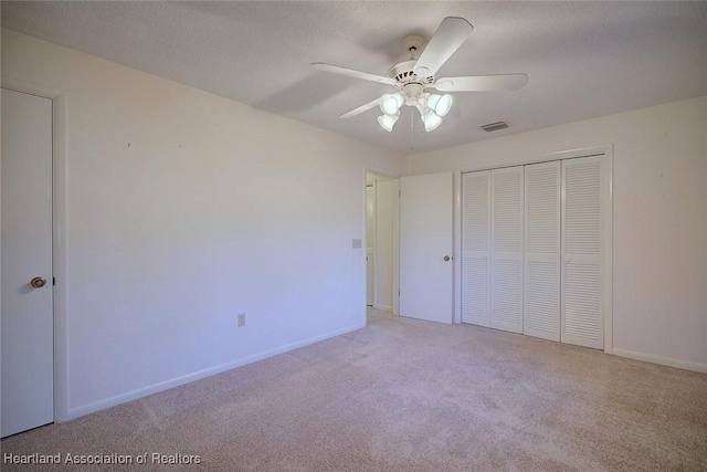 unfurnished bedroom featuring visible vents, carpet, a closet, and a textured ceiling