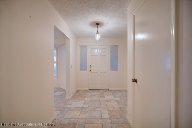 entryway featuring a textured ceiling and baseboards