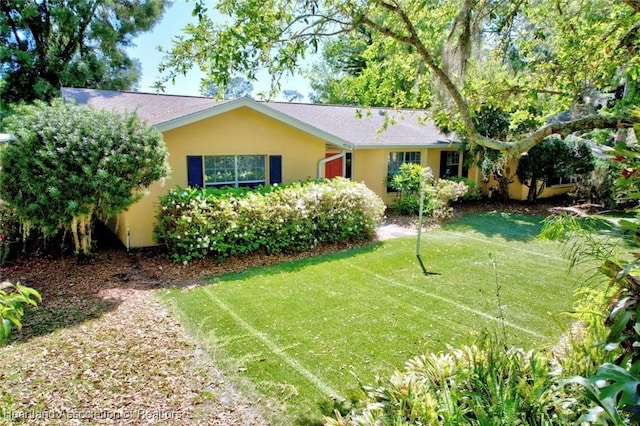 ranch-style house featuring a front lawn, roof with shingles, and stucco siding