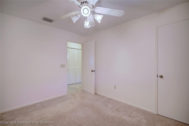 empty room with light carpet, visible vents, baseboards, and a ceiling fan